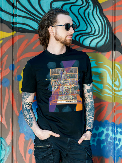 Black T-shirt with a vibrant graphic design of a modular synthesizer with patch cables and knobs on the background with orange and purple geometric colorful elements.