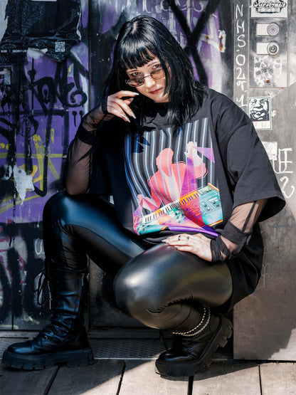 Black T-shirt with a colorful design of a man playing on a synthesizer and purple light beams go out of his hands.