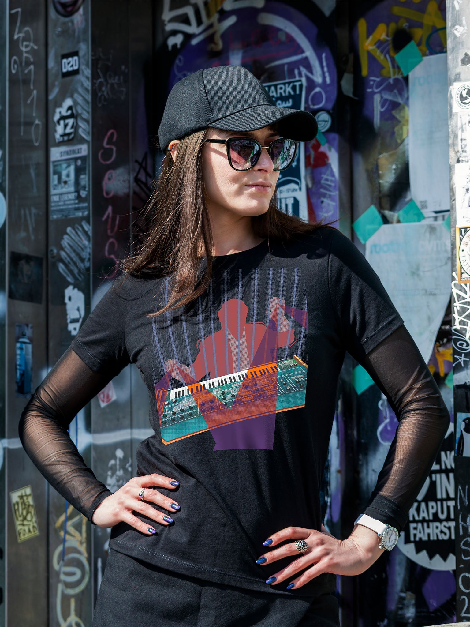 Black T-shirt with a colorful design of a man playing on a synthesizer and purple light beams go out of his hands.