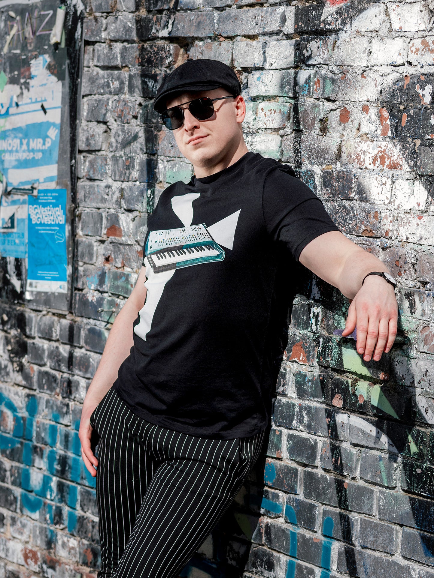 Black T-shirt with a design of a synthesizer and white geometrical light beams go out of the synth.